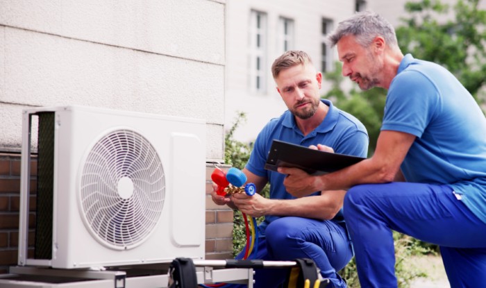 HVAC technicians reviewing an outdoor air conditioning unit in Englewood, CO