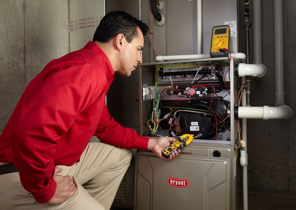 Heating and air conditioning technician servicing an indoor furnace in Englewood, CO