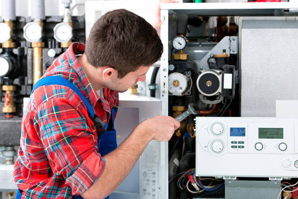 HVAC technician inspecting and repairing boiler controls in Englewood