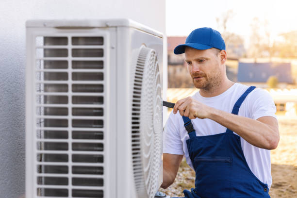 HVAC technician servicing an outdoor air conditioning unit in Englewood